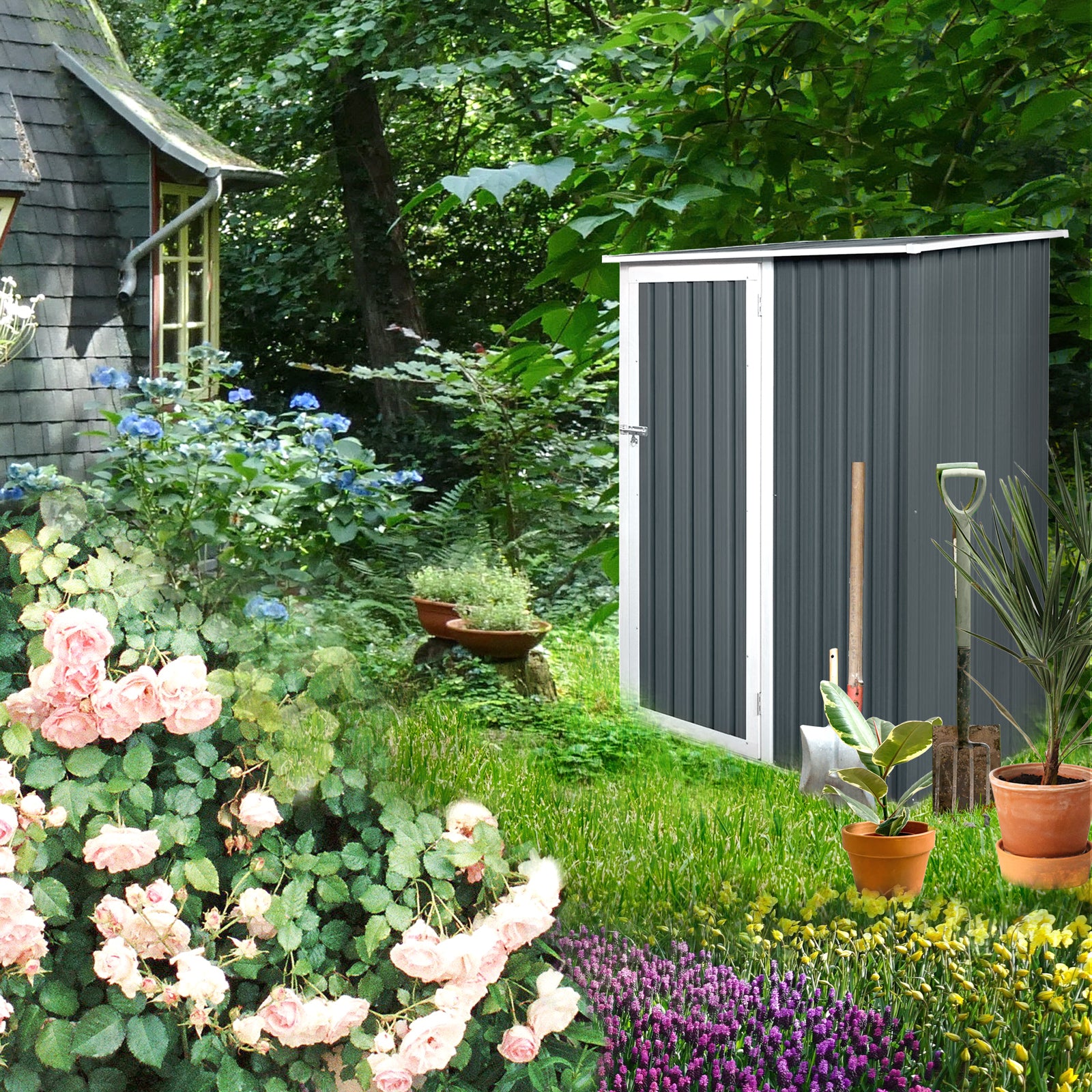 Kleiner anthrazitfarbener Gartenschuppen mit weißem Rahmen neben einem Haus, umgeben von grünen Pflanzen, Rosen und bunten Blumen